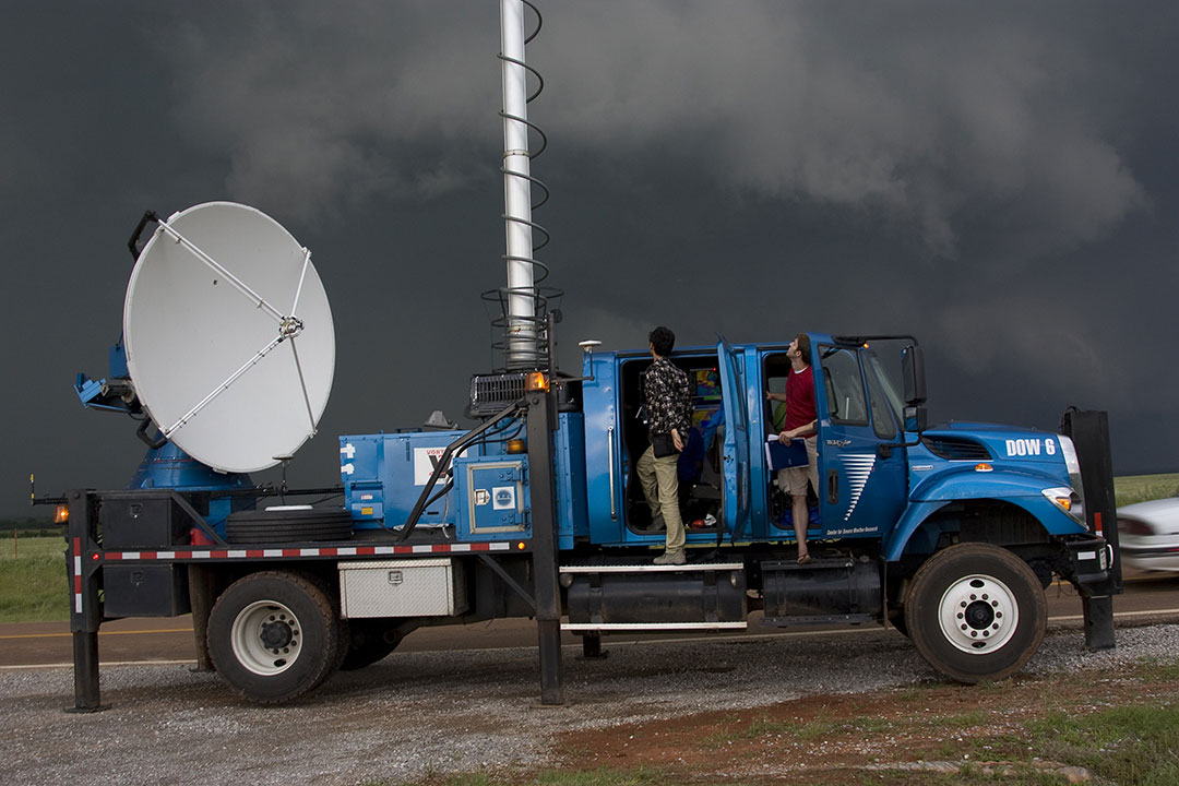 weather utilities truck with equipment and two men looking up at the sky